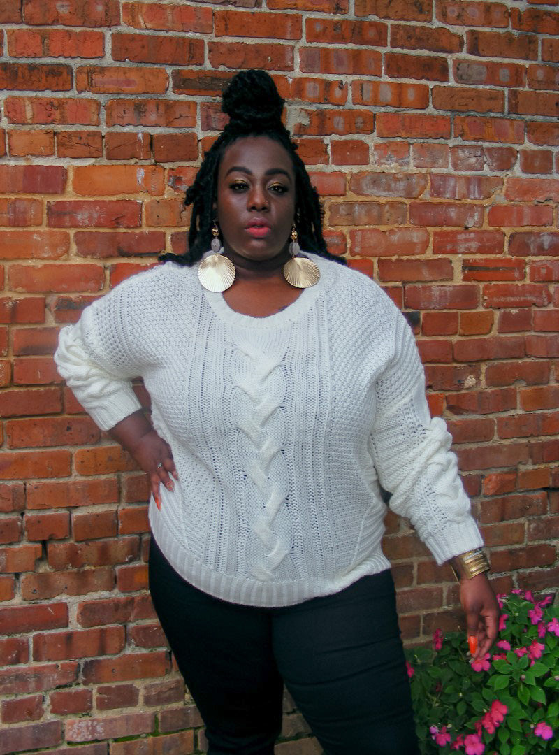  Carmen is an ivory white, medium knit sweater with a fun braided pattern along the center front. This sweater is perfect for the fall and can be paired in endless ways. Shop the Carmen Sweater today.